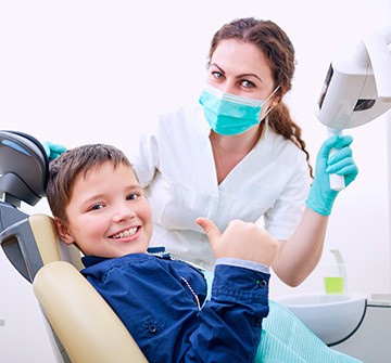 Little boy giving a thumbs up in the dentist’s chair