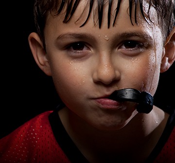 Young child biting down on athletic mouthguard