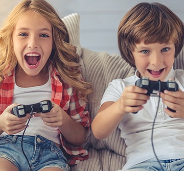 Kids playing video games after tooth-colored filling treatment