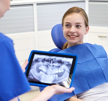Dentist looking at child's digital x-rays on tablet computer
