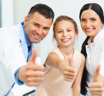 Dental team smiling with young female patient 