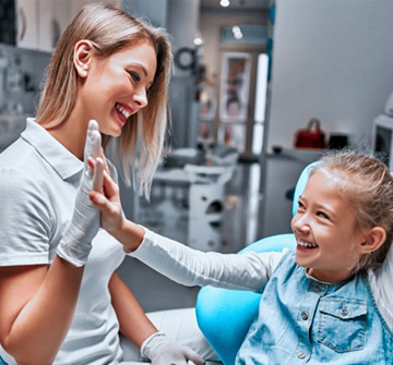 Dentist and little girl giving each other a high five 