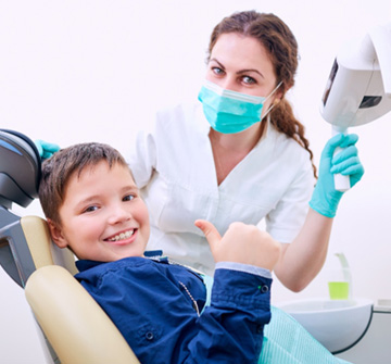 A young boy giving a thumbs up in the treatment chair 