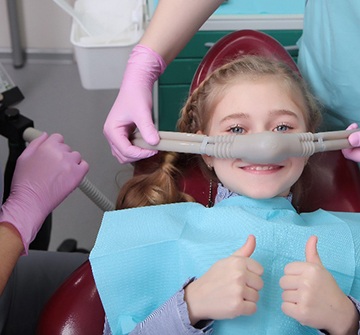Child giving thumbs up while inhaling nitrous oxide