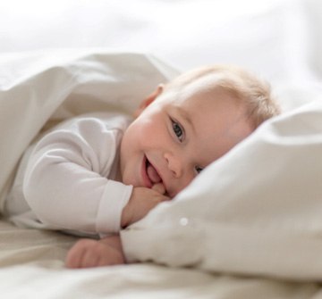 happy baby in bed before teething in Nashua 