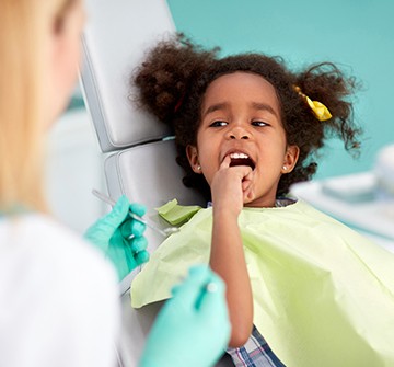 Child pointing to smile during dental checkup and teeth cleaning at dentistry for toddlers visit