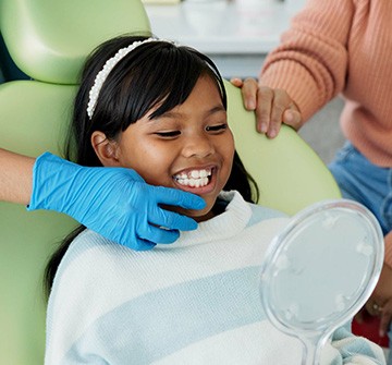 Pediatric dental patient looking at her smile in mirror