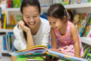 a parent and a child smiling while reading together